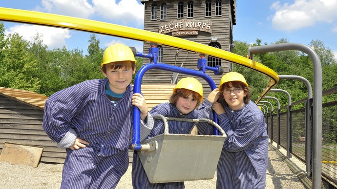 Drei Kinder in Bergmannskleidung vor einer Lore auf der Zeche Knirps Drei Kinder in Bergmannskleidung vor einer Lore auf der Zeche Knirps