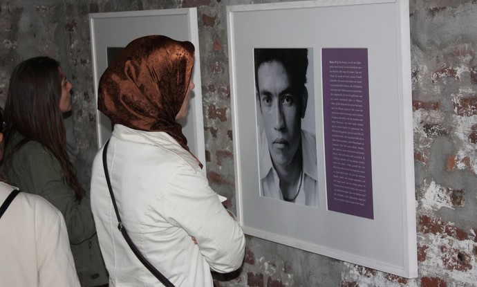 Eine Frau mit Kopftuch sieht sich Fotografien einer Ausstellung an. Eine Frau mit Kopftuch sieht sich Fotografien einer Ausstellung an.